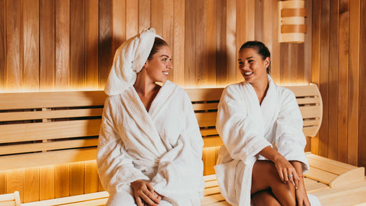 Två kvinnor sitter i bastu efter spa och hudvårdsbehandling – illustration för återhämtning efter microneedling.
