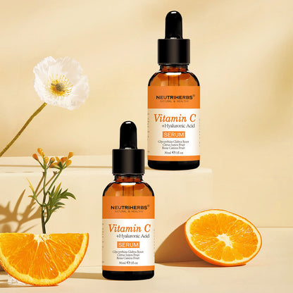 Neutriherbs Vitamin C + Hyaluronic Acid Serum 30 ml sammen med friske appelsiner og blomster. Inspirerende produktbillede, som fremhæver serummets indhold af C-vitamin til fugtet hud, øget glød og en mere ensartet hudtone.